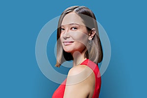 Headshot portrait of young trendy woman looking at camera on blue background