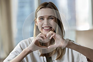 Headshot portrait young woman showing heart symbol with fingers