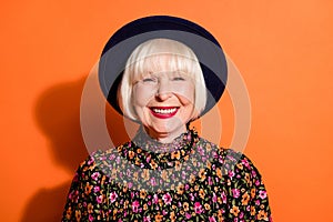 Headshot of positive laughing stylish granny wearing printed blouse hat smiling with red lipstick isolated on bright