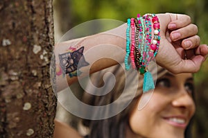 Headshot pretty brunette, standing between trees, bare skinned arms above head pose, sensually looking into camera