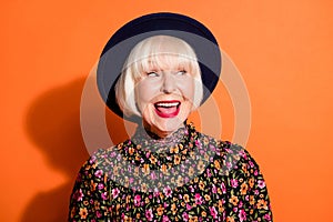 Headshot of sly curious old woman looking blank space smiling red lipstick wearing blouse headwear isolated vivid orange