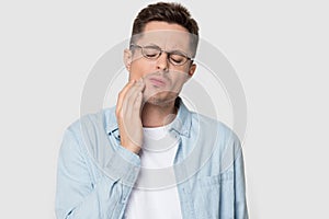 Headshot studio portrait man in glasses suffers from tooth ache