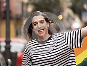 Headshot of a transgender woman smiling and walking in a urban street. Concept of pride and transgender community