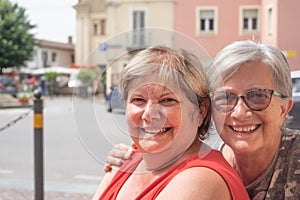 Headshot of two women with positive expression, cuddle each other, posing for family portrait. People, emotions and friendship