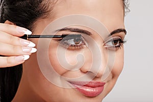Headshot woman applying mascara