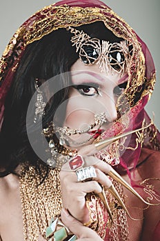 Headshot woman dressed in traditional hindu clothing, heavily decorated in gold and elegant veil, extremely long