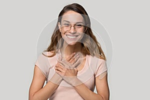 Headshot woman in glasses feels grateful holding hands on chest