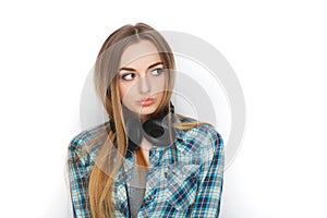 Headshot of a young adorable blonde woman in blue plaid shirt enjoying listening music to big professional dj headphones.