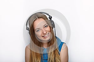 Headshot of young adorable blonde woman with cute smile wearing big black professional monitoring headphones against white studio