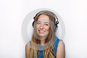 Headshot of young adorable blonde woman with cute smile wearing big black professional monitoring headphones against white studio