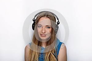 Headshot of young adorable blonde woman with cute smile wearing big black professional monitoring headphones against white studio