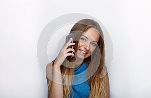 Headshot of young adorable blonde woman with cute smile on white background texting on her smartphone