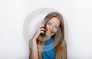 Headshot of young adorable blonde woman with cute smile on white background texting on her smartphone