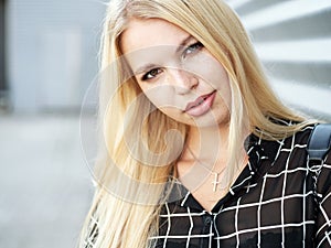 Headshot of young beautiful excited woman with gorgeous natural lips, blue and brown eyes in black blouse on urban metal strips ba