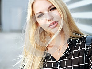 Headshot of young beautiful excited woman with gorgeous natural lips, blue and brown eyes in black blouse on urban metal strips ba