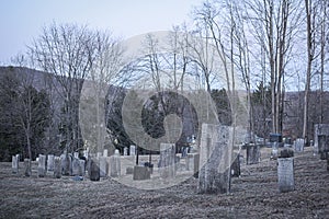 Headstones at an old delapidated looking graveyard on a gray gloomy day in Upstate New York