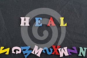 HEAL word on black board background composed from colorful abc alphabet block wooden letters, copy space for ad text. Learning