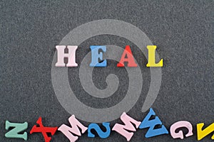 HEAL word on black board background composed from colorful abc alphabet block wooden letters, copy space for ad text. Learning