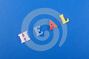 HEAL word on blue background composed from colorful abc alphabet block wooden letters, copy space for ad text. Learning english