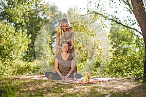 Healer applies her massage skills on her client on the grass.