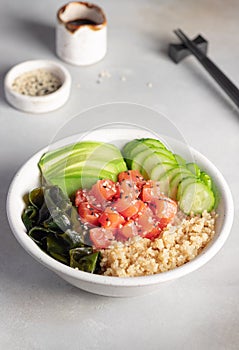 Healhty lunch bowl with quinoa, salmon, wakame seaweed, avocado and cucumber.