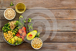 Healhty vegan lunch bowl. Avocado, quinoa, sweet potato, tomato, spinach and chickpeas vegetables salad on wooden table