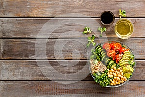 Healhty vegan lunch bowl. Avocado, quinoa, sweet potato, tomato, spinach and chickpeas vegetables salad on wooden table