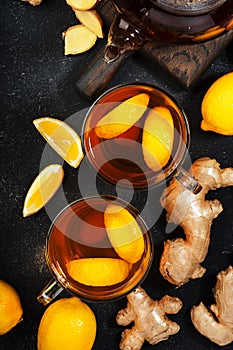 Healing black herbal tea with ginger, honey, lemon and sage. Immune booster drink in glass cup on black kitchen table background