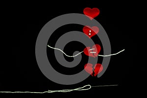 Healing broken heart concept  red heart is sewn with white thread with needle on black background