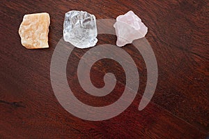 Healing crystals: Rose quartz, Calcite and a Clear quartz on a table. Gemstones are used for their positive vibrations to bring