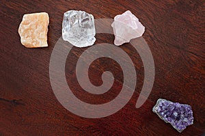Healing crystals on a wooden table, including: Clear Quartz, calcite, amethyst and rose quartz. Gemstones are used for their