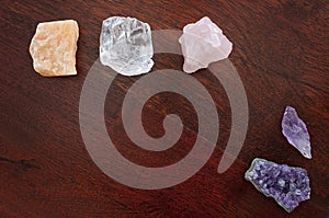 Healing crystals on a wooden table, including: Clear Quartz, calcite, amethyst and rose quartz. Gemstones are used for their