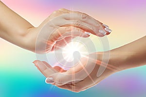 Healing hands with bright sunburst on rainbow background