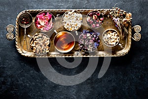 Healing Herbs and Herbal tea in a metal tray on a dark concrete background, top view