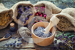 Healing herbs in hessian bags, wooden mortar with dry lavender