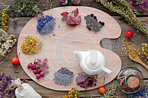 Healing herbs on wooden palette and tea kettle, top view.