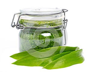 Wild garlic leaves in front of a glass with wild garlic pesto