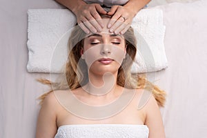 Healing touch of an alternative medicine practicioner touching with fingers a forehead of an attractive young women