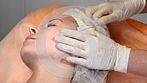 Healtcare clinic. Young female client gets thread face lifting procedure. Beautician in gloves making face anti-aging to