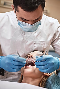 Health is all we do. Attractive woman at the dental office. Dentist examining patient`s teeth in clinic.