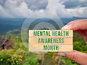 Health Awareness Concept - mental health awareness month text on wooden blocks with nature background. Stock photo.