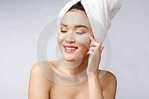 Health and beauty concept - Attractive asian woman applying cream on her skin, on white.