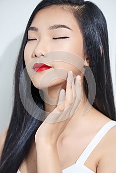 Health and beauty concept - face of beautiful woman touching her cheek with closed eyes