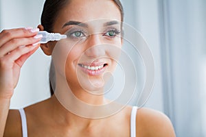 Health and Beauty. Eye Care. Beautiful Young Woman Holding Drops