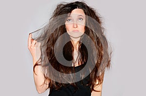 Health and beauty. Young woman looking at split ends. Hair tips