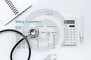 Health care billing statement with doctor`s stethoscope on white background top view mock-up photo
