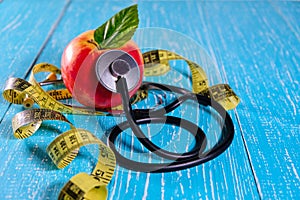 Health care check up and Lose weight for health. Tape measure for body, apple and Stethoscope on wooden desk