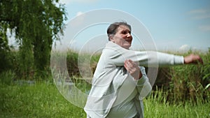 Health care, cheerful elderly woman goes in for sports does exercises for hands during an outdoor workout