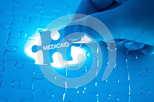 Health Care Concept. Doctor holding a jigsaw puzzle with MEDICAID word. photo