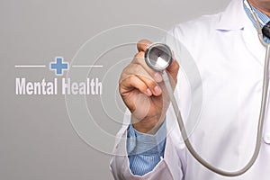 Health Care Concept. Doctor holding a stethoscope and Mental Health word on gray background.